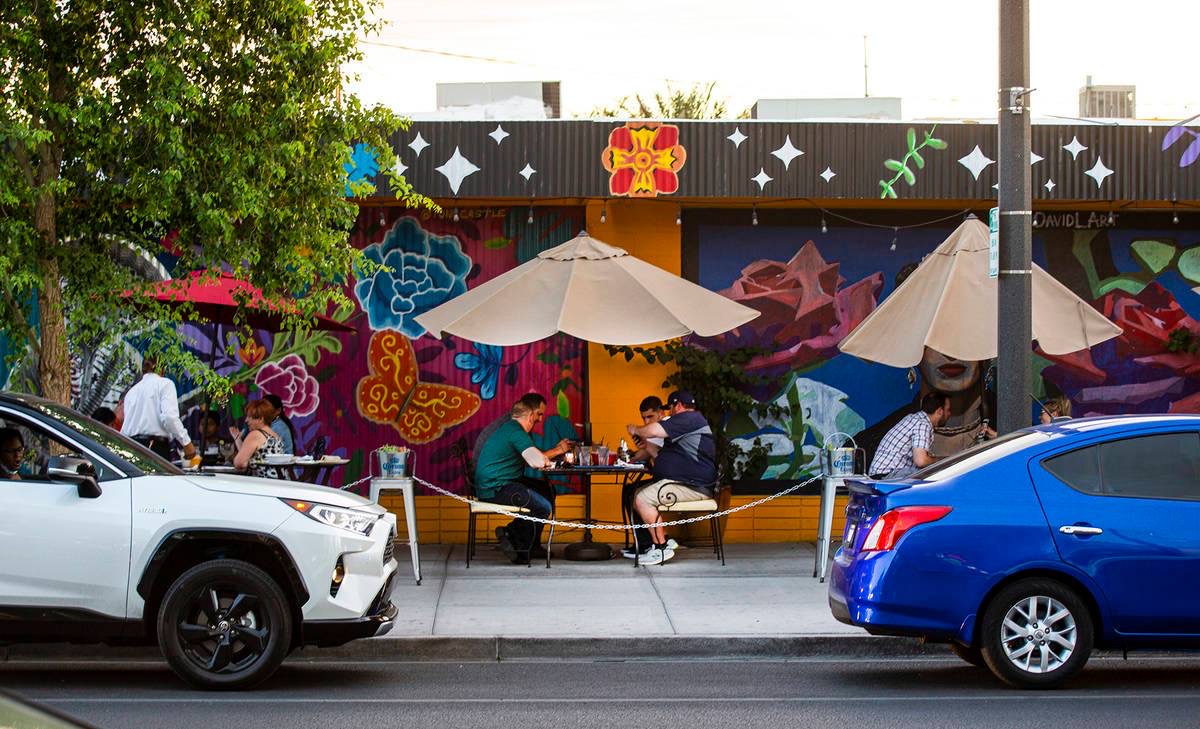 Diners on a patio in front of a floral mural